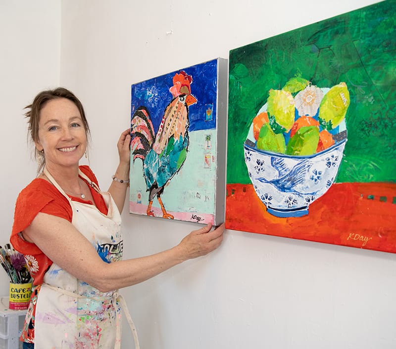 kellie day hanging rooster painting on her studio wall.